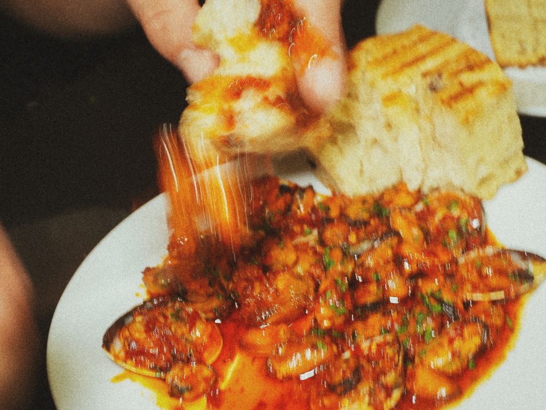 Bread dipped into spicy mussels